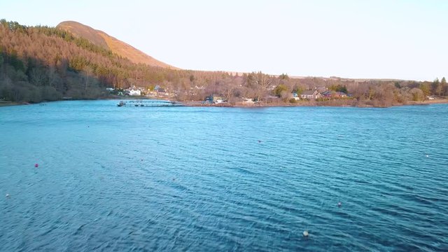 Drone forward shot at the Highlands of Scotland during golden hour, over loch lomond flying towards Balmaha. 4K video quality