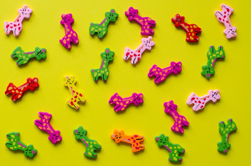 Toy giraffes on yellow background. Colorful wooden giraffes.
