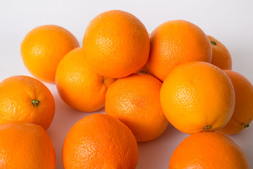 Pile of whole orange fruits isolated on white background. High angle, closeup. Natural vitamin or organic food concept