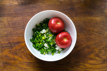 Tomato salad with basil, olive oil and balsamic vinegar in bowl over wooden background