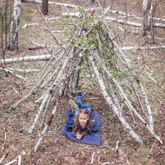 Girl chatting on mobile phone in the built stick hut house in birch forest, walking in nature © Maria