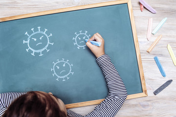 child drawing coronavirus on a blackboard