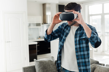 Man in plaid shirt using virtual reality headset at home