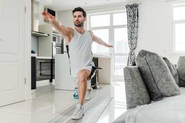 Handsome man in sportswear doing lunges while training at home