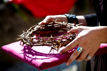 Crown of thorns held on a pillow by female hands