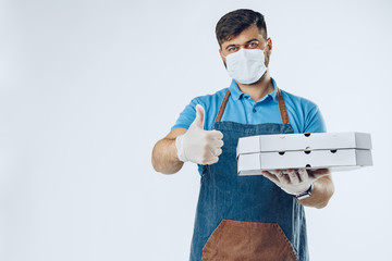 Fototapeta na wymiar Pizza delivery man in medical gloves and mask against grey background. Safe service while coronavirus covid-19 outbreak