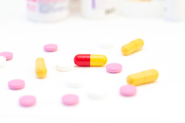 pills and capsules of different colors on the background of many drugs. The concept of health care, treatment, illness.