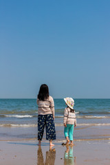 初夏の海で砂遊びをしている子供姉妹