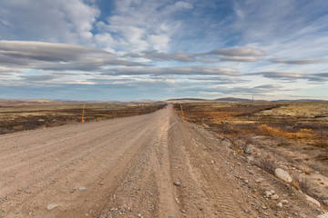 Fototapeta na wymiar Gravel road to Teriberka in northern tundra landscape of Kola Peninsula. Natural scenery in autumn season. Murmansk Oblast, Russia