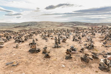 Touristic pyramid balanced stack of stones at the summer tundra. Way to Teriberka, Kola Peninsula, Russia.