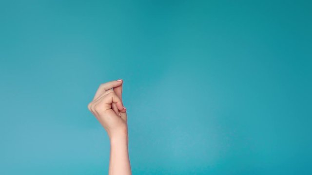 Woman hand snaps her fingers over blue background. Female hand with snapping fingers on blue screen background. Snapping fingers of caucasian woman hand 4k