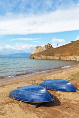 Baikal Olkhon Island. On a sandy beach near the village of Khuzhir is deserted. Blue pleasure boats await tourists after quarantine in a bay near the famous Shaman rock