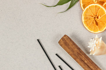 Incense sticks with a stand, sliced orange circles in a wooden bowl on a gray background. Also a seashell.Aromatherapy. The concept of home Spa.