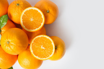 Bright juicy whole and sliced orange fruits with leaves isolated on white background. Closeup, top view, copy space. Natural vitamin or organic food concept
