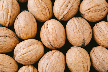 Walnuts with shells on dark background. Background of fresh whole walnuts.
