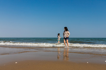 海岸で海遊ぶをしている子供姉妹
