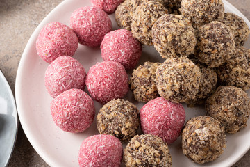 Raspberry-coconut truffles and truffle with walnuts on a gray plate.