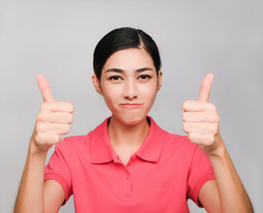 young beautiful asian woman wore pink t shirt, Thumbs up,perfect and Correct expression , on gray background