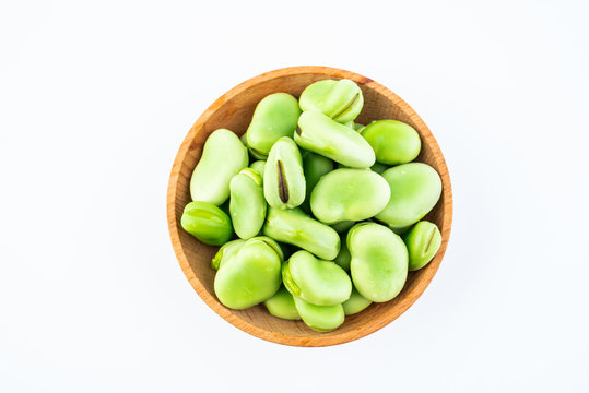 Fresh broad beans in a saucer on white background