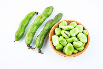 Fresh broad bean pods and broad beans on white background