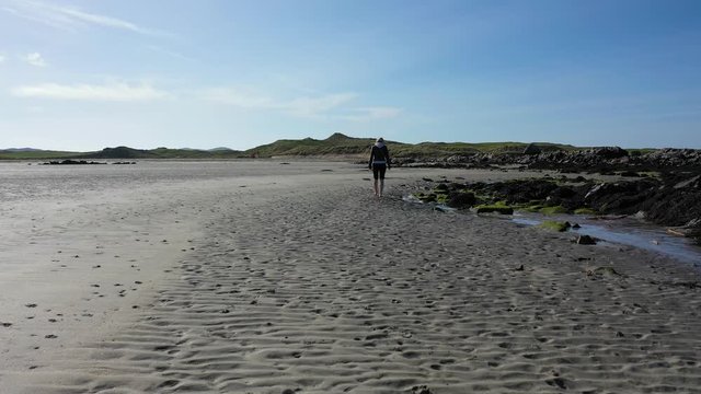 Pretty lady walking on lonely sandy beach