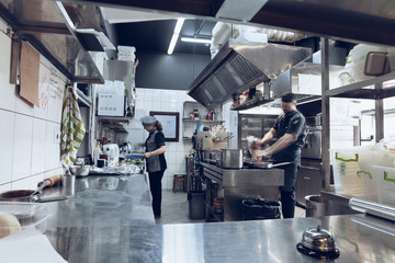Behind the scenes of brands. The chef cooking in a professional kitchen of a restaurant meal for client or delivery. Open business from the inside. Meals during the quarantine. Hurrying up, motion.