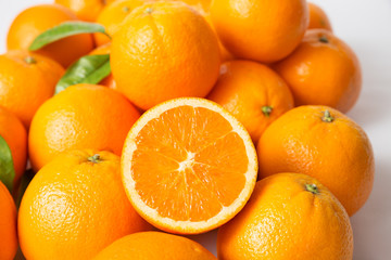 Heap of ripe juicy orange fruits with green leaves. Closeup, top view. Natural vitamin or organic food concept