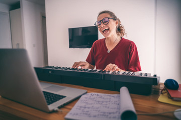 Young girl woman learns to sing and play the piano from a video conference from a laptop in internet. Education video calls self education