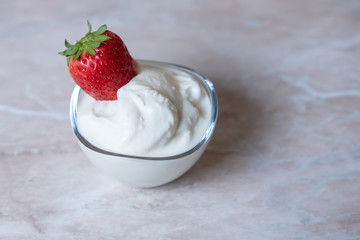 cream in a transparent plate and strawberries