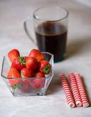 a cup of coffee and a strawberry with a transparent plate