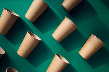 Eco friendly craft paper cups on green background.
