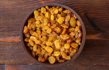 Dry golden raisins in wooden bowl, top view