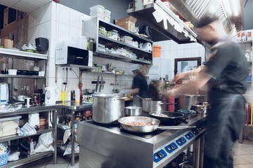 Behind the scenes of brands. The chef cooking in a professional kitchen of a restaurant meal for client or delivery. Open business from the inside. Meals during the quarantine. Hurrying up, motion.