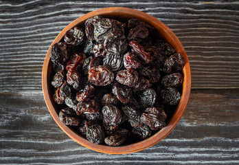 Prunes in wooden bowl top view