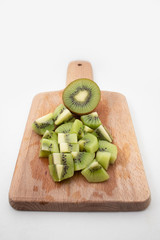 Cut half and pieces of juicy kiwi fruit on chopping board isolated on white background. Organic food or healthy nutrition concept