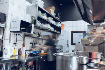 Behind the scenes of brands. The chef cooking in a professional kitchen of a restaurant meal for client or delivery. Open business from the inside. Meals during the quarantine. Hurrying up, motion.