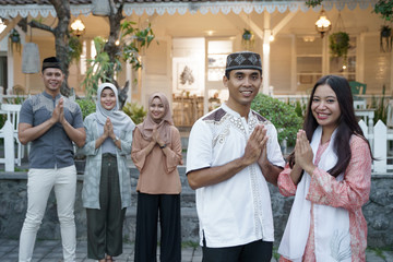 muslim asian couple smiling to camera standing in front of their house