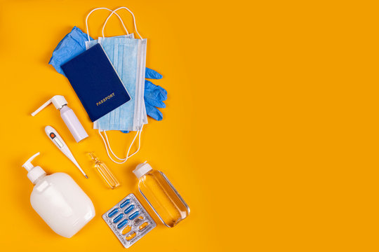 Coronavirus new lifestyle concept. Passports, sanitizer, thermometer, medical gloves, sanitizer gel, blue capsules pill in blister and medical mask on yellow colored background, flat lay