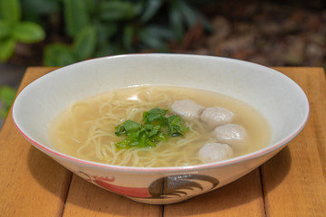 Egg noodles with pork ball and vegetable in bowl.