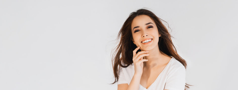 Beauty fashion portrait of smiling sensual asian young woman with dark long hair in white shirt on white background banner