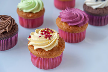 different cupcakes on a light glass surface close up