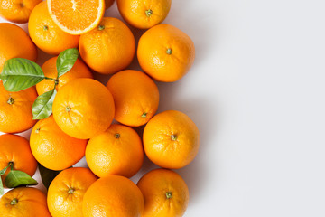 Bright juicy ripe orange fruits with leaves isolated on white background. Closeup, top view, copy space. Natural vitamin or organic food concept