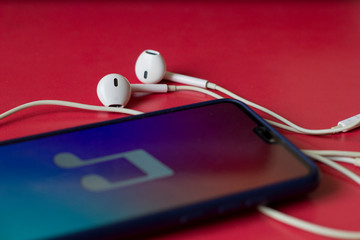 Close-up of smart phone with headphones on a red background. (Top view). Listen to music.
