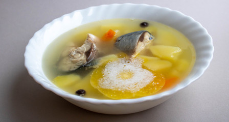 Delicious hot fish soup from sea fish in a white plate on a gray table