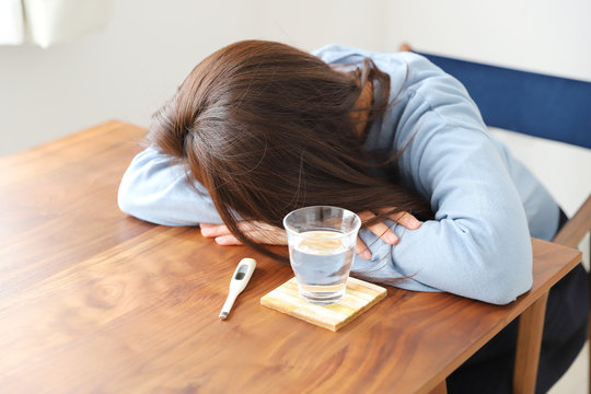 体調不良でテーブルに横たわる女性