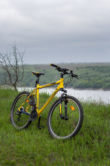 Fototapeta na wymiar Yellow bicycle on green grass by the river