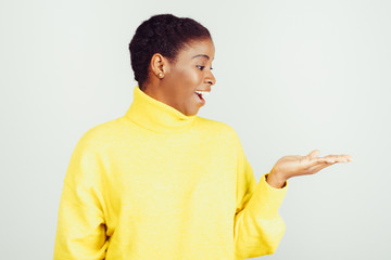 Surprised woman looking at copy space on palm. Beautiful happy young African American woman gesturing showing something on palm isolated on white background. Advertisement concept