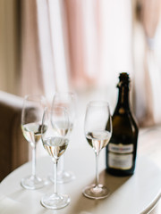 four wine glasses and an open bottle of prosecco