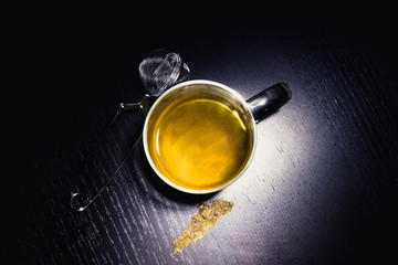 Tea in a glass mug over black wood desk