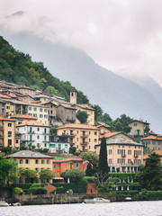 Italy. Lake Como. Green high mountains in the clouds with small houses and villages in red, yellow and white colors. down below is Lake Como. Overcast